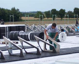 Man installs solar base frames on a green roof